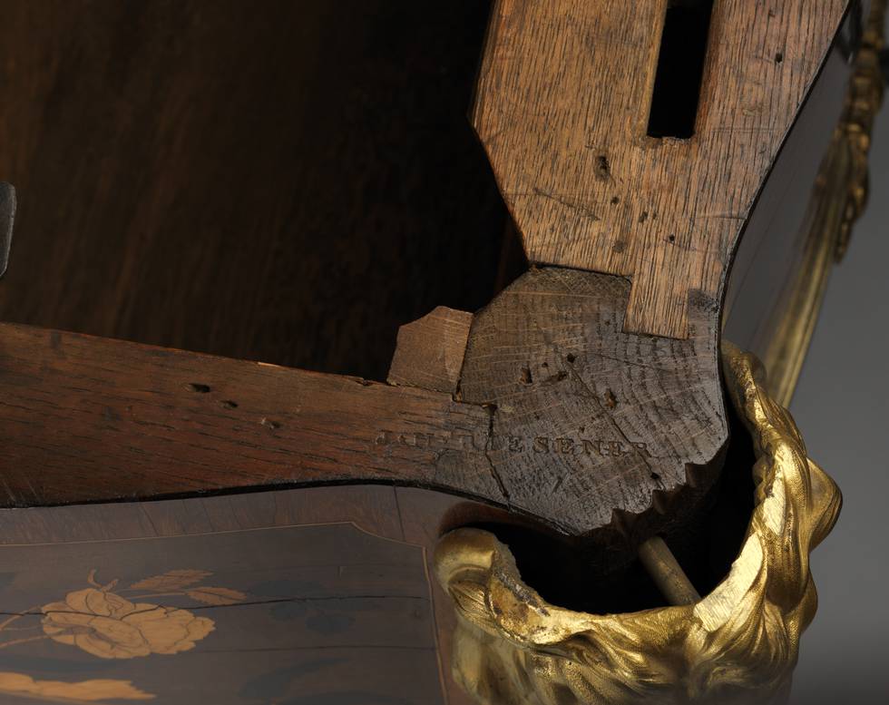 A detail of J. H. RIESENER stamped onto the carcase of a marquetry roll-top desk