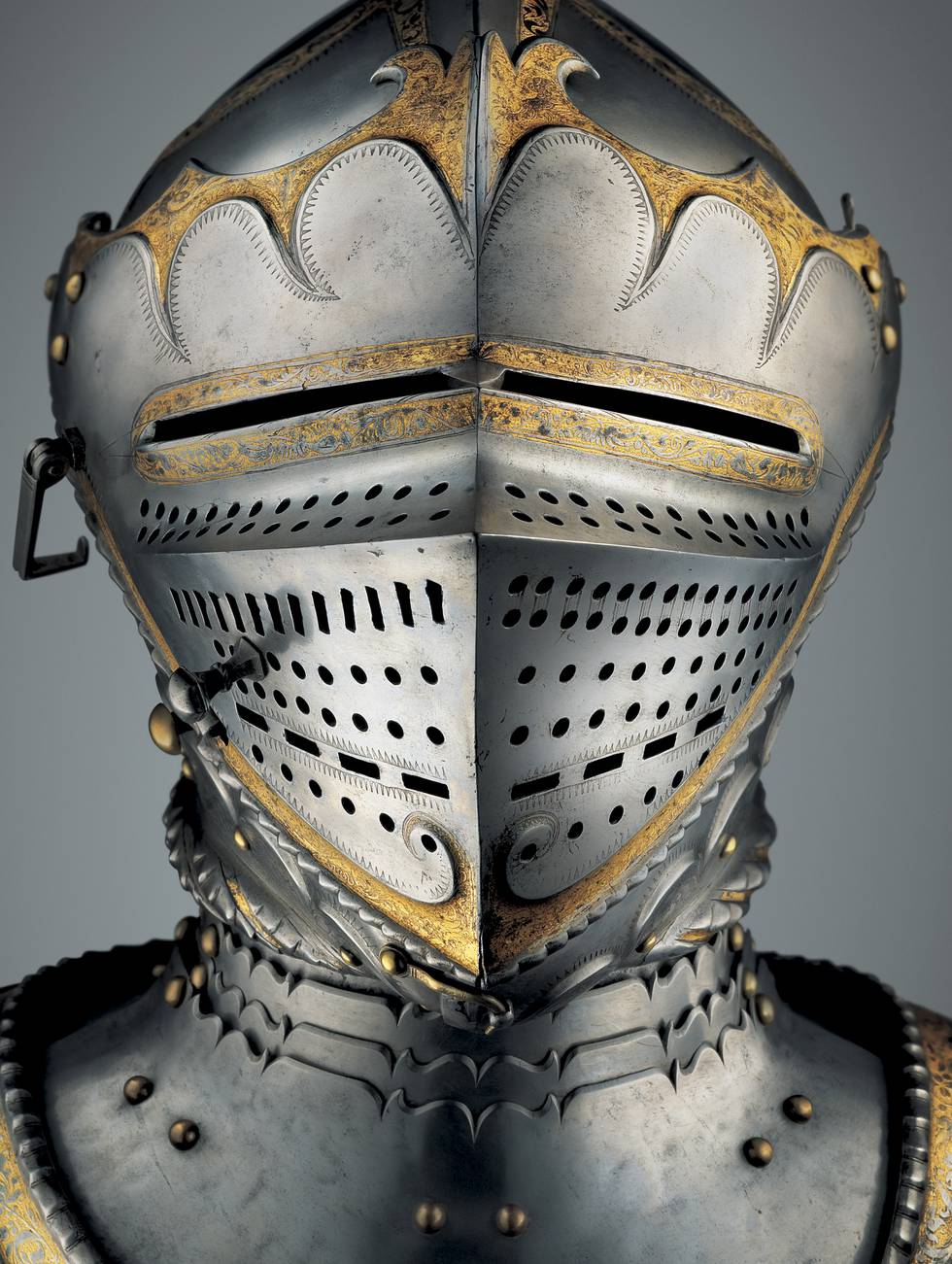 Close up photograph of a gold and heavily etched armoured helmet