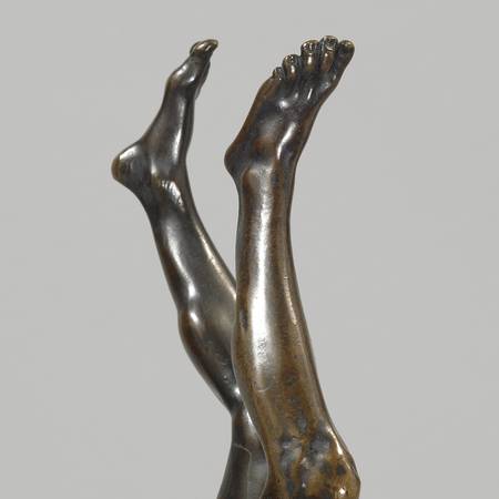 Detail of bronze sculpture of mans legs doing a handstand